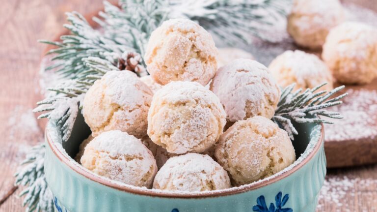 Almond Snowball Cookies arranged on a rustic wooden table, with a light dusting of powdered sugar creating a wintry, holiday-inspired dessert scene.