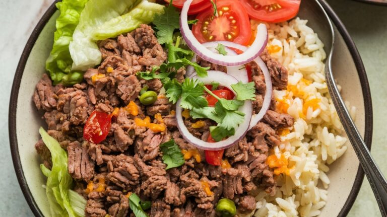 "A vibrant loaded taco bowl delight, filled with seasoned ground beef, fresh lettuce, tomatoes, cheese, and topped with a dollop of sour cream and crunchy tortilla chips